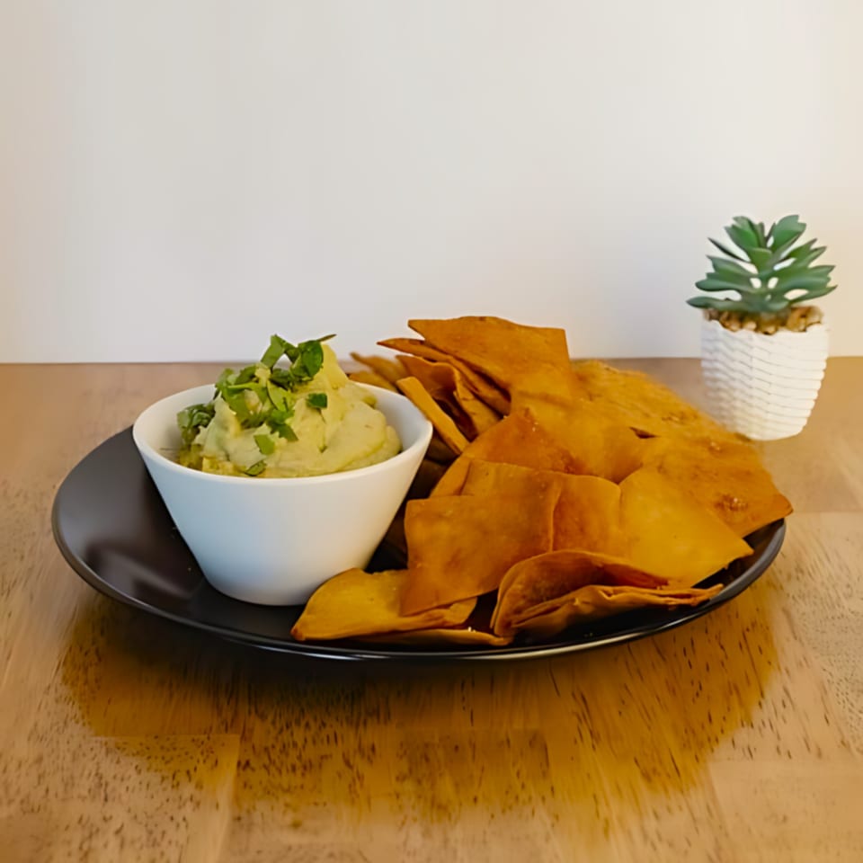 Guacamole topped with cilantro, served with tortilla chips on a black plate at Fearless Coffee & Kitchen.